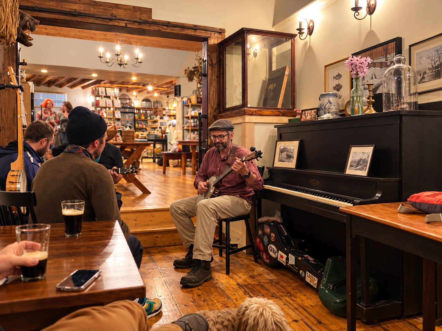 A banjo player beside the upright piano at a music session inside Davoll's General Store, friends with pints in the foreground.