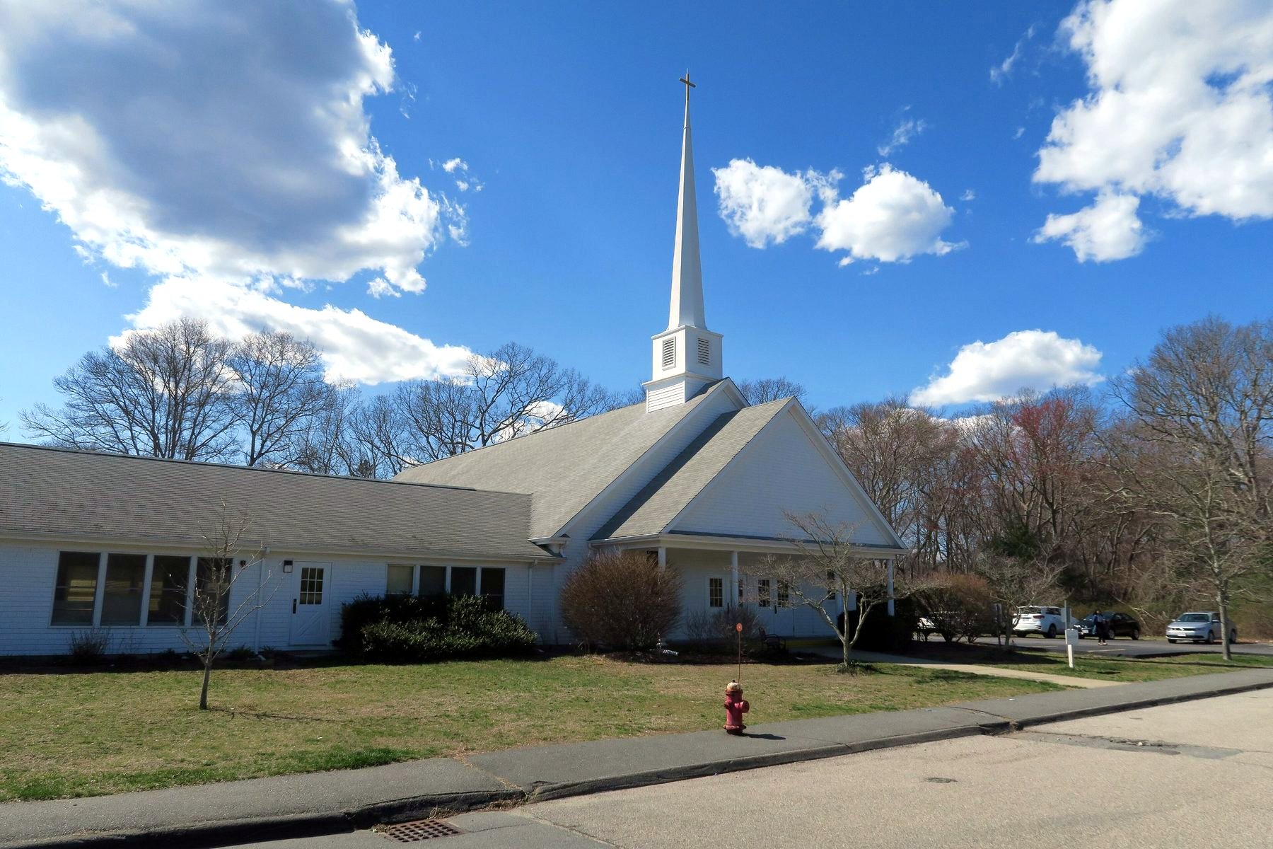 Smith Mills Congregational Church, white with a tall steeple, under a blue sky.